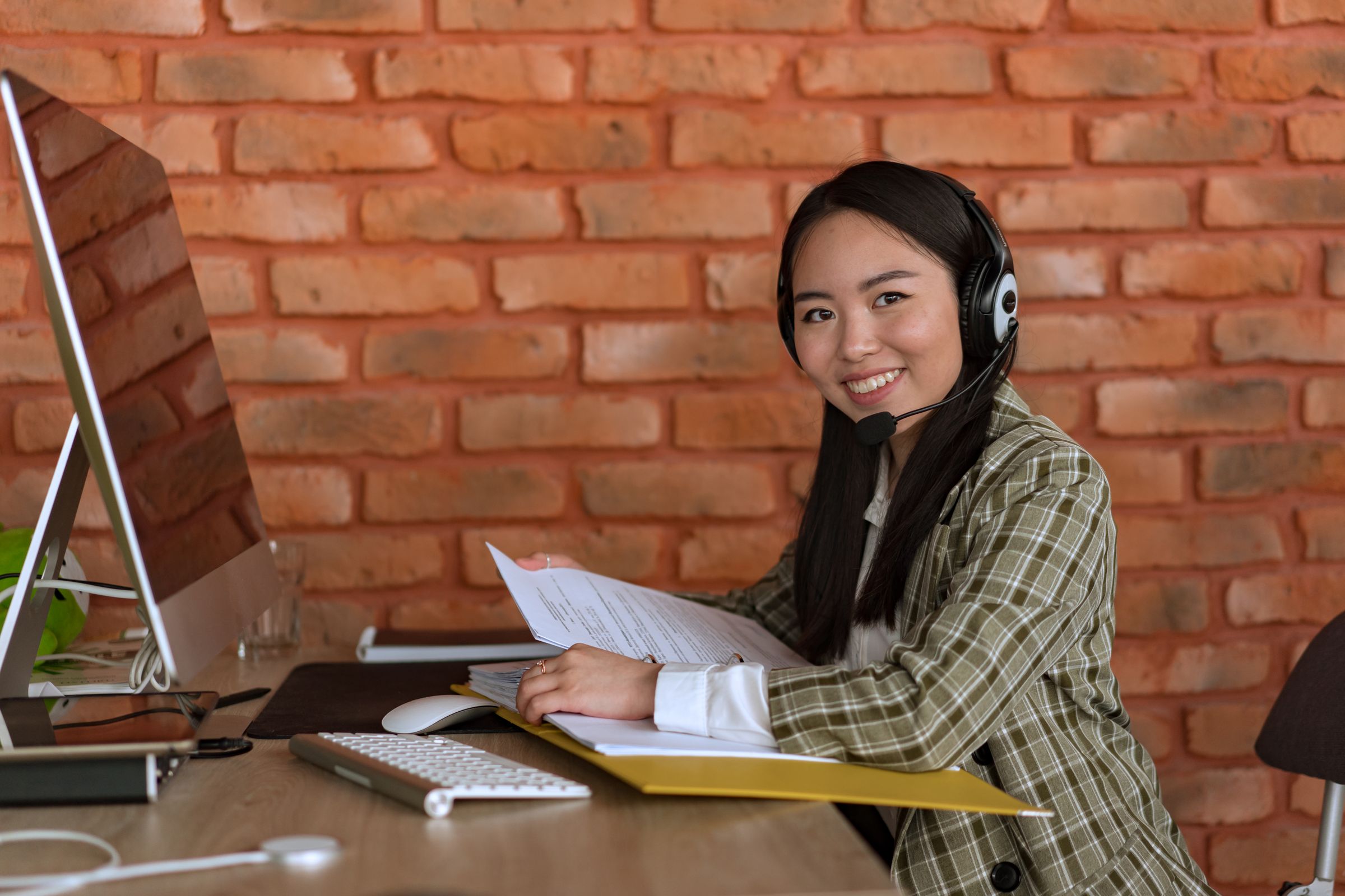 Smiling support specialist wearing a headset at her desk.
