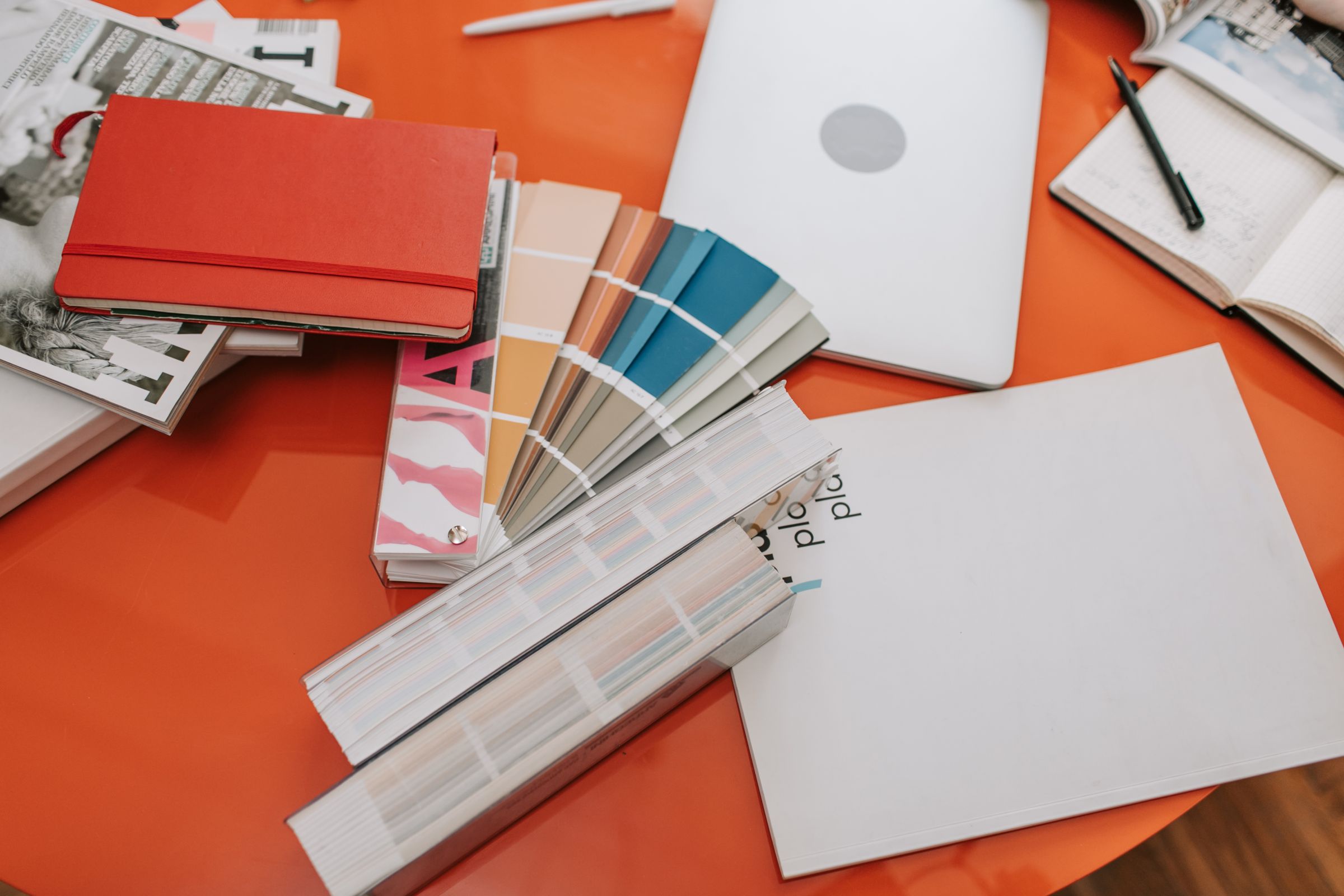 Colour swatch fans, notebooks and stationery on a designer's desk.