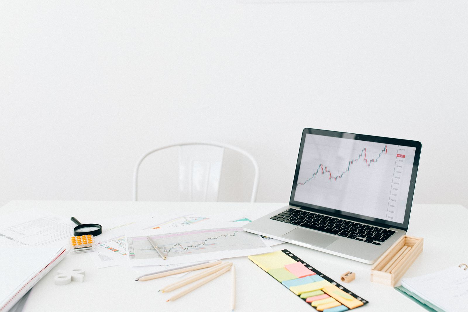 Laptop showing charts on a white desk.