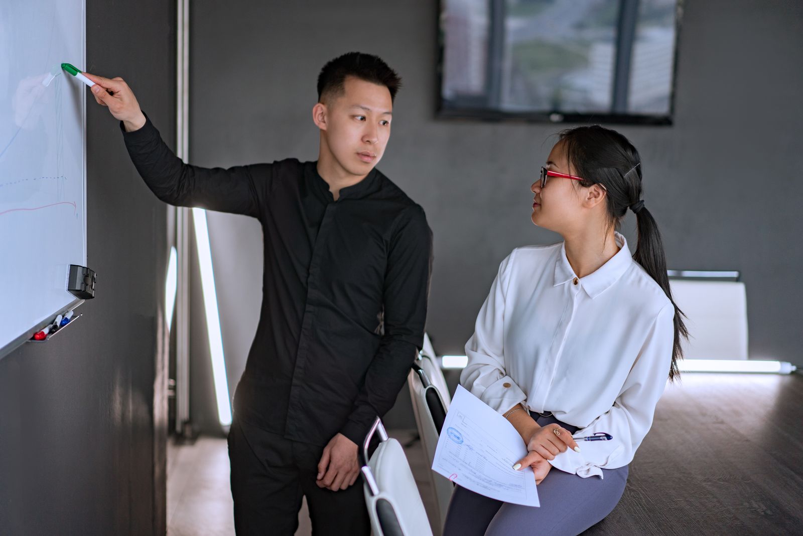 Consultant mapping a solution on a board with a colleague.