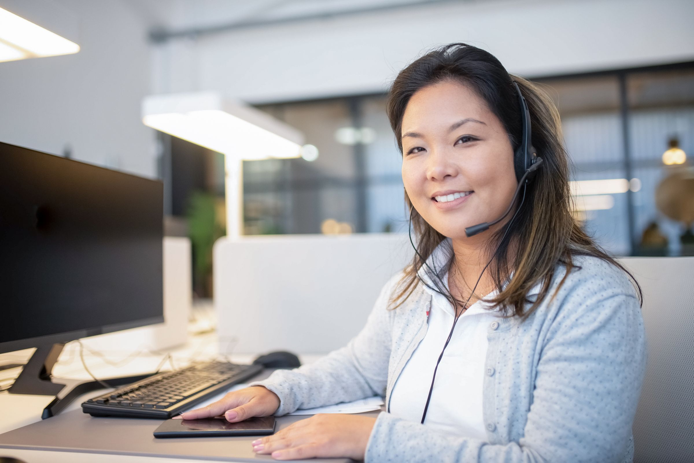 Smiling support specialist wearing a headset at her desk.